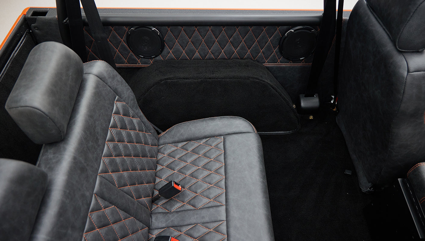 Rear bench seat and black carpet with quilted black and orange interior panels in Classic Ford Bronco