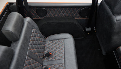 Rear bench seat and black carpet with quilted black and orange interior panels in Classic Ford Bronco