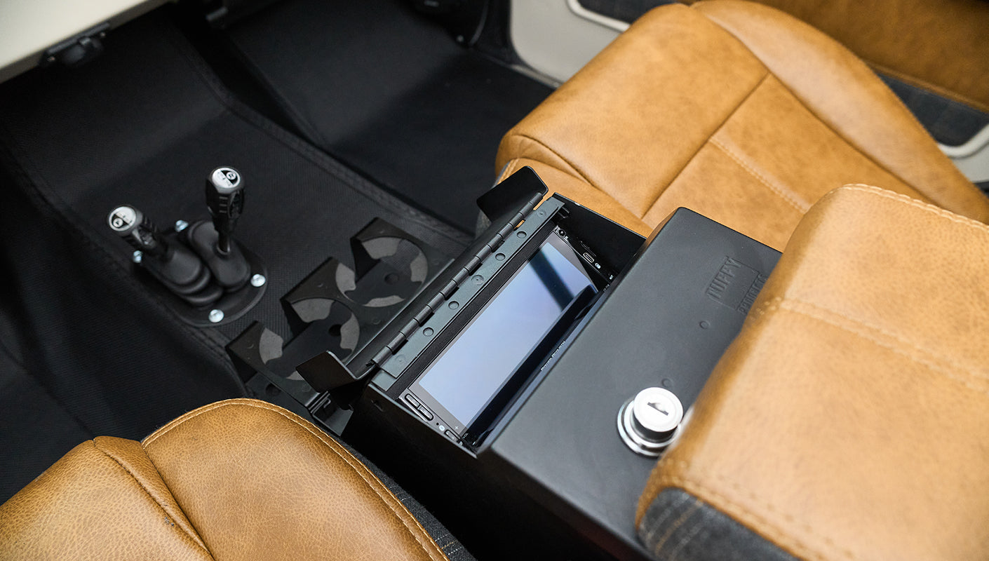 Center console with touchscreen display, cup holders, and two gear shift levers between tan leather seats