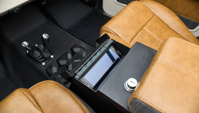 Center console with touchscreen display, cup holders, and two gear shift levers between tan leather seats
