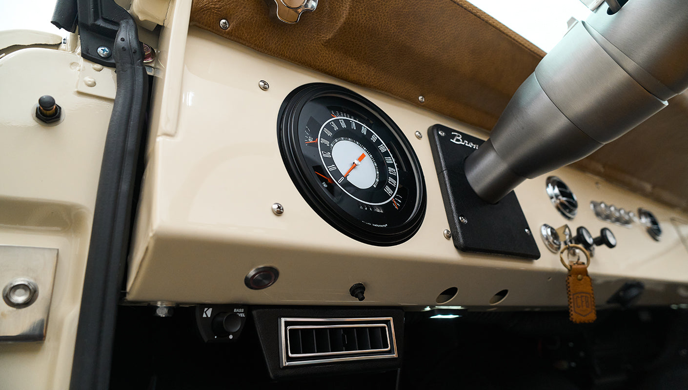 Close-up of speedometer and controls on cream dashboard with Bronco badge