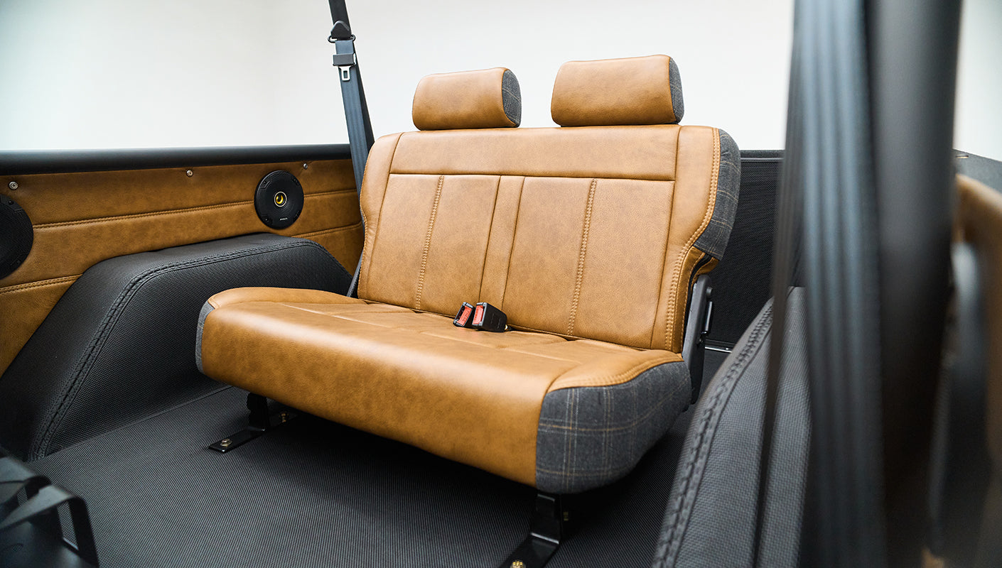Rear seats in Classic Ford Bronco featuring brown leather and plaid side panels with seat belts