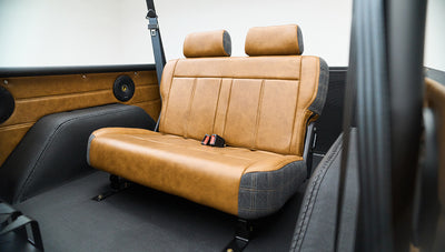 Rear seats in Classic Ford Bronco featuring brown leather and plaid side panels with seat belts