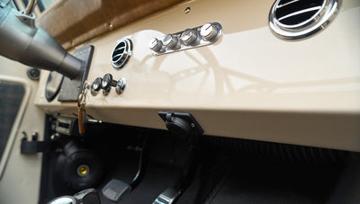 Dashboard controls and air vents with key on leather keychain hanging from ignition