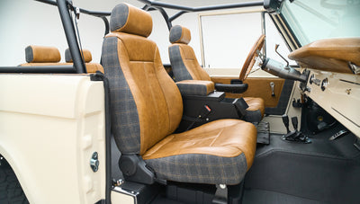 Classic Ford Bronco interior showing driver and passenger seats with brown leather and plaid fabric