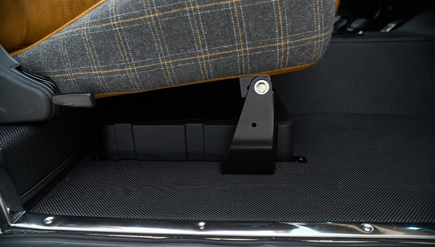 Under passenger seat area showing black floor mat and seat mounting bracket