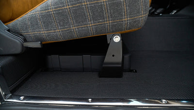 Under passenger seat area showing black floor mat and seat mounting bracket
