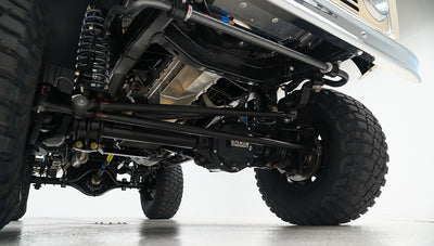 Underneath view of vehicle suspension and drivetrain components with large off-road tires