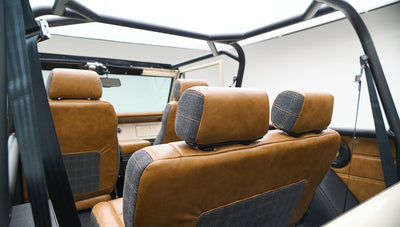 Interior view of rear seats in tan and gray upholstery with roll cage