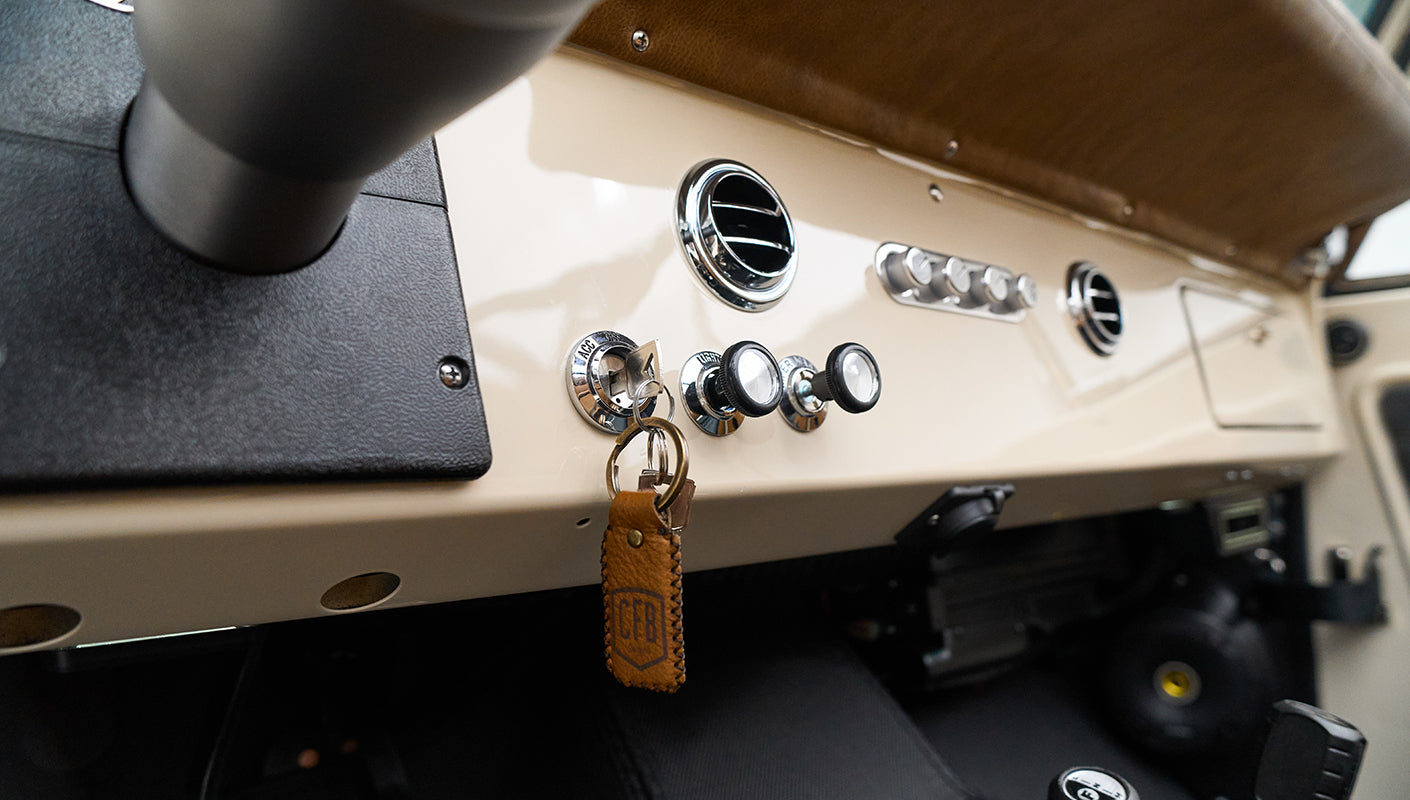 Classic Ford Bronco interior showing beige dashboard with air vents, knobs, and controls
