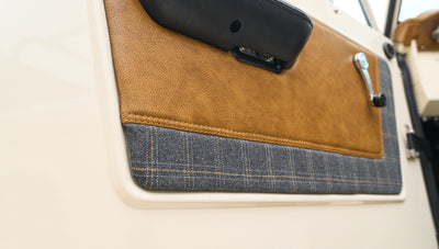 Close-up of Classic Ford Bronco door panel with plaid fabric and brown leather details