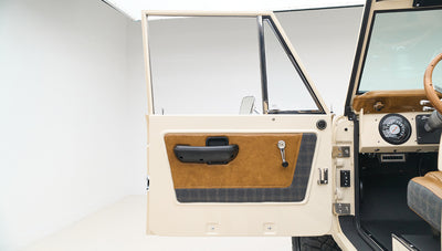 Classic Ford Bronco driver side door open, showing interior panel and handle