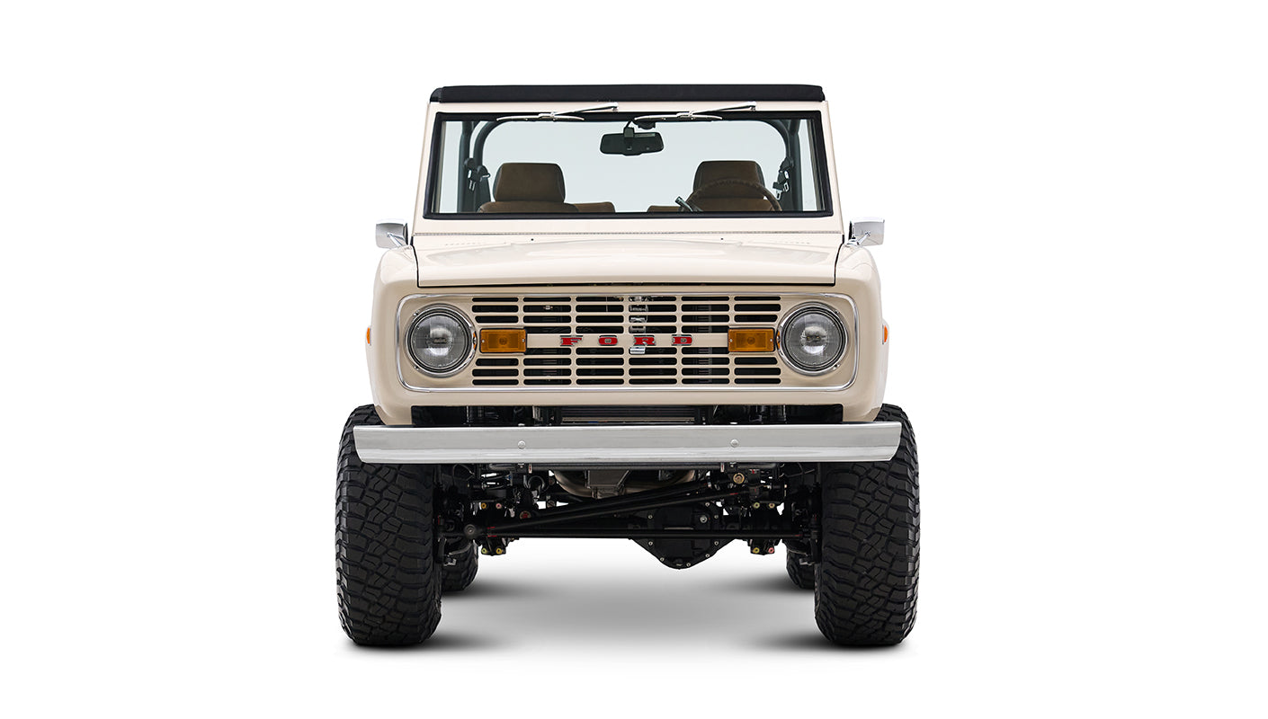 Front view of cream Classic Ford Bronco with off-road tires and black roll bars