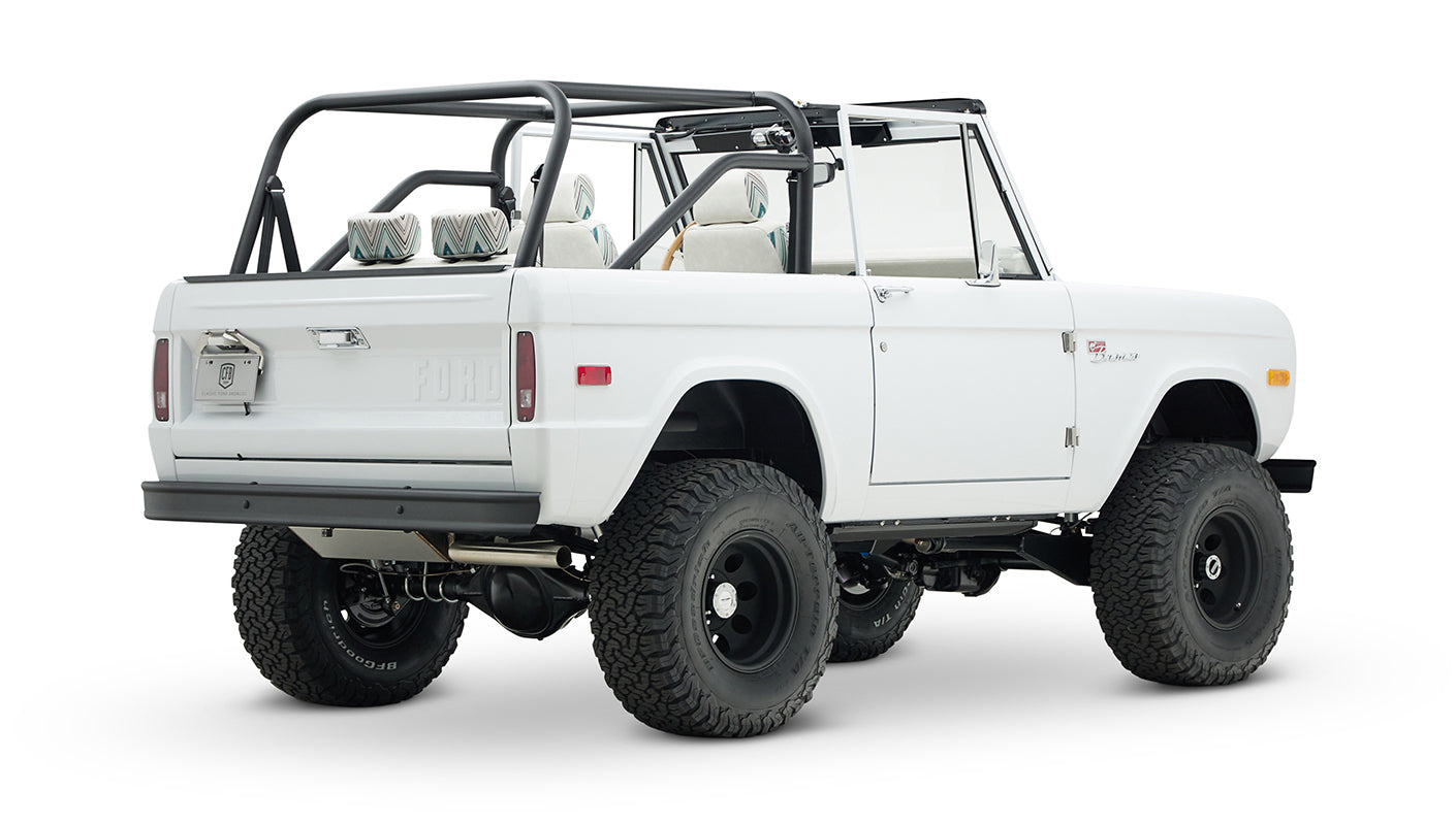 Classic Ford Bronco 1966 white open-top vehicle from rear-side angle with black wheels and tires