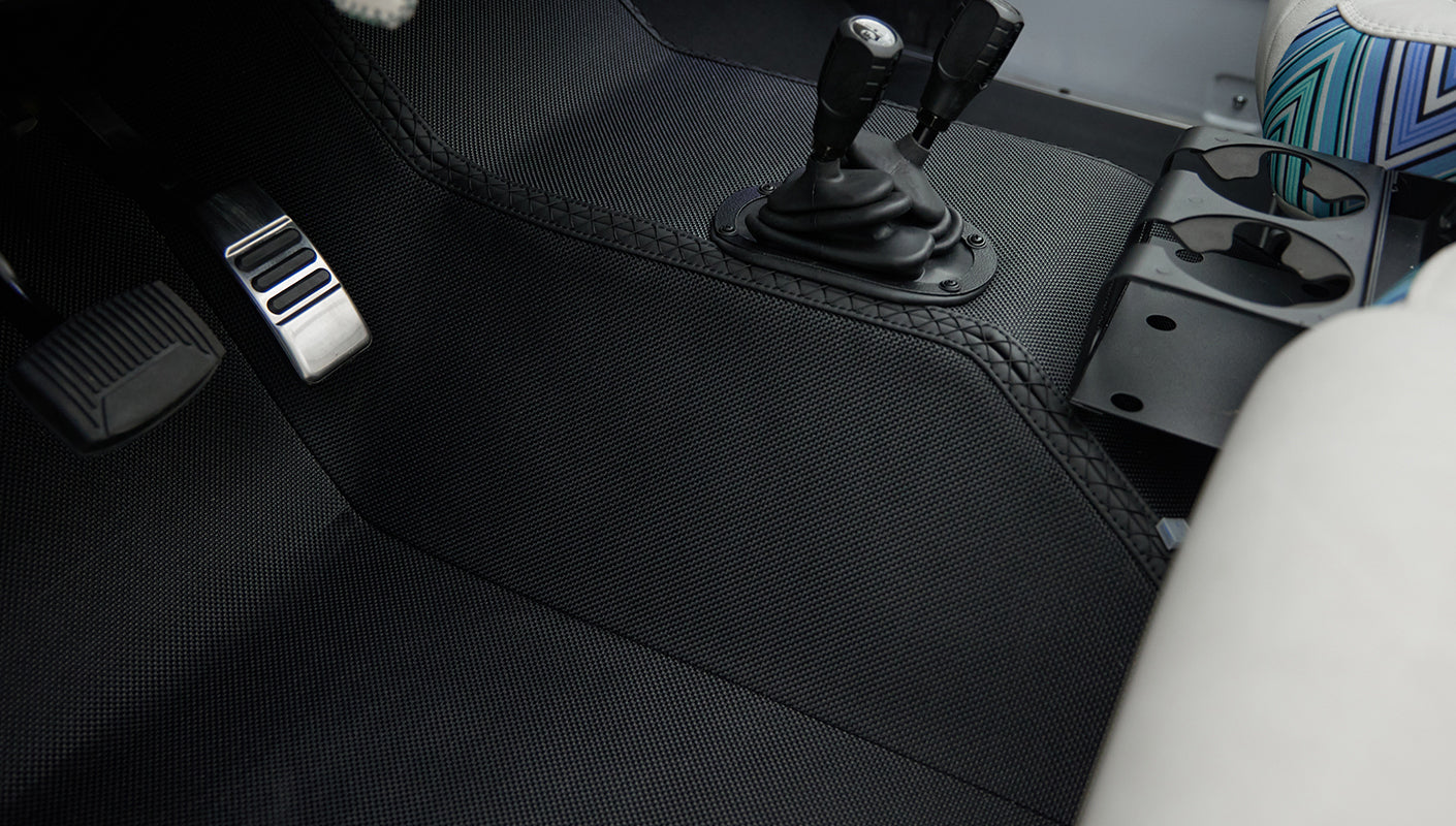 Close-up of Classic Ford Bronco floor area with pedals and textured black floor mat