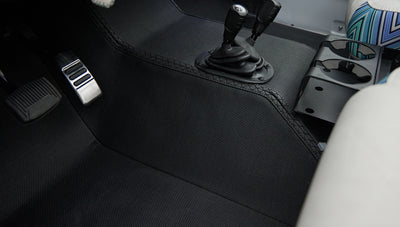 Close-up of Classic Ford Bronco floor area with pedals and textured black floor mat