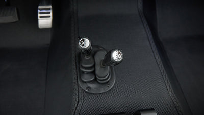 Close-up of gear shift levers on the floor with black textured mat in Classic Ford Bronco