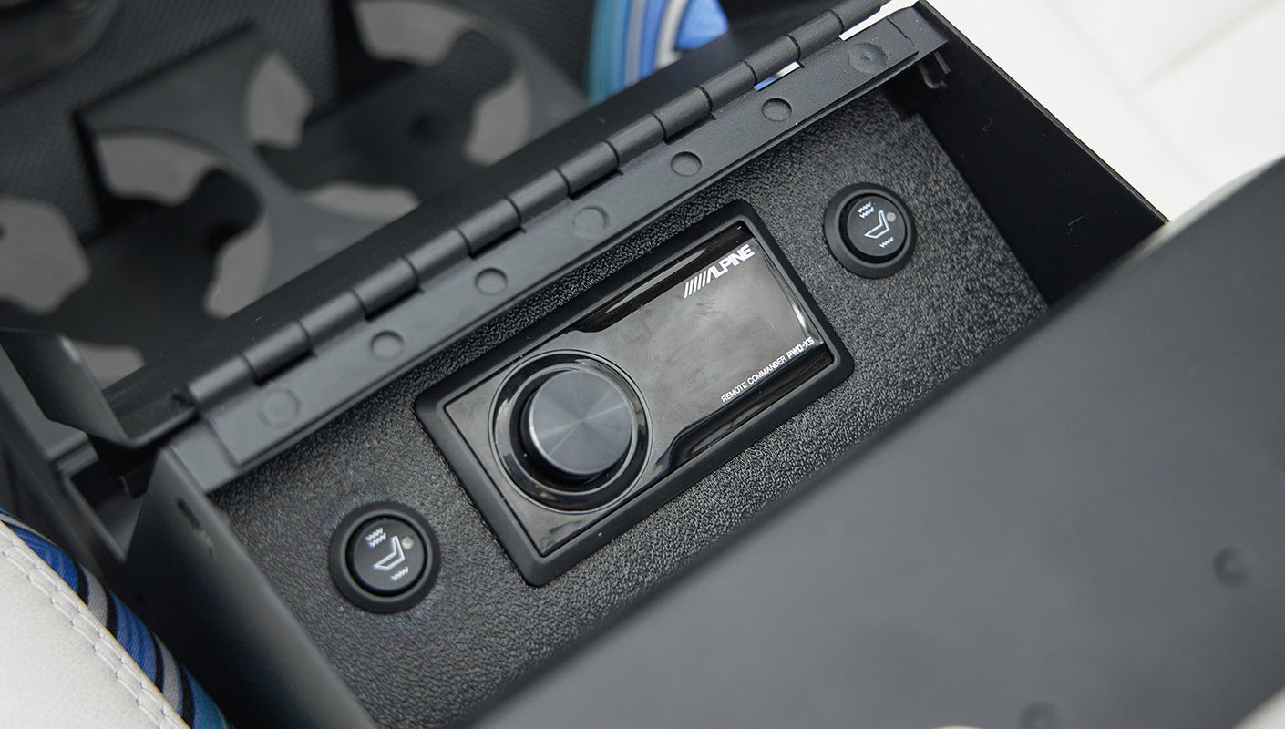 Open center console storage with Alpine audio controls and heated seat buttons in Classic Ford Bronco