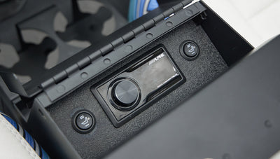 Open center console storage with Alpine audio controls and heated seat buttons in Classic Ford Bronco