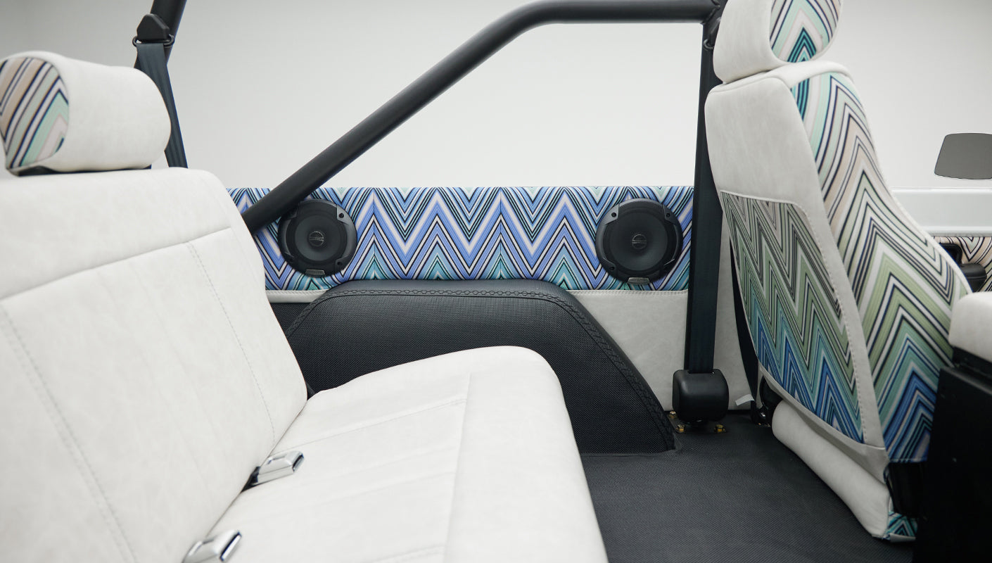 Classic Ford Bronco seats with white upholstery and patterned accents under a black roll bar