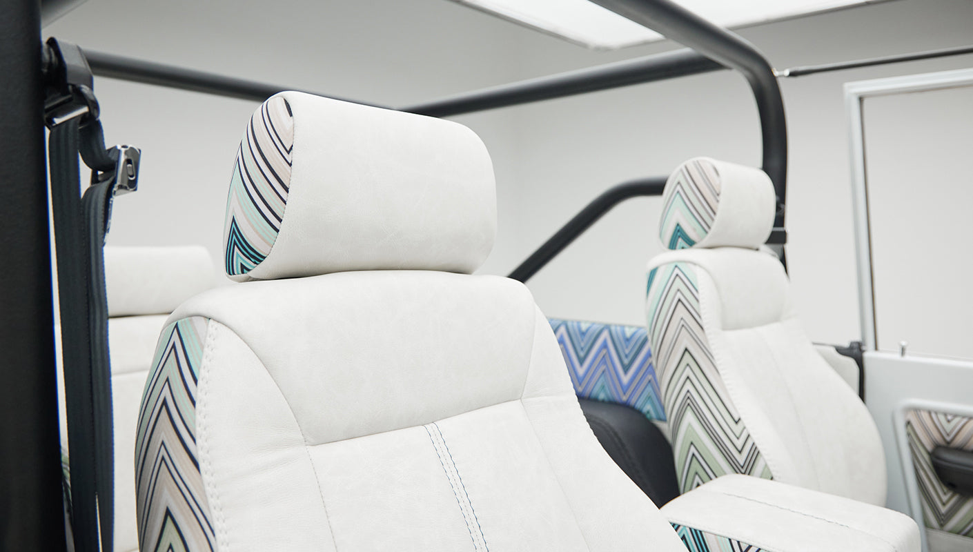 Two front bucket seats with white upholstery and patterned inserts in Classic Ford Bronco