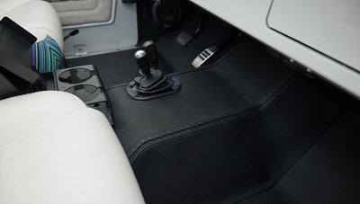 White and blue patterned seat with black floor mat and two gear shift knobs in vehicle interior