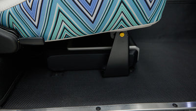 Close-up of car seat base with blue and green zigzag patterned fabric and black floor mat