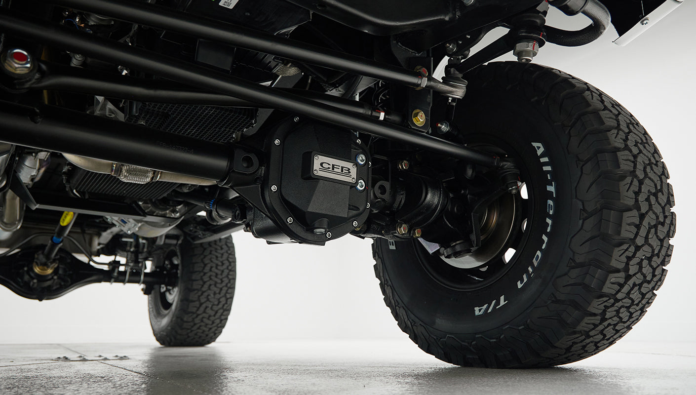 Undercarriage view focused on black differential with CFB badge and tire with white lettering