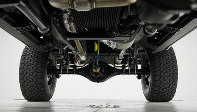 Undercarriage view showing black suspension components, axles, and rugged tires