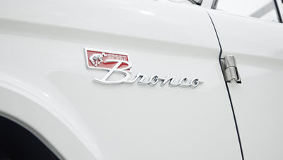 Close-up of Classic Ford Bronco's front fender emblem on white body