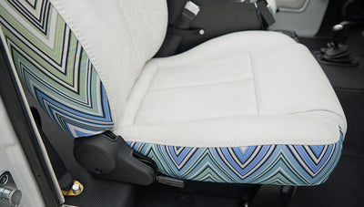 Close-up of white seat showing zigzag blue pattern on side and black floor mat underneath