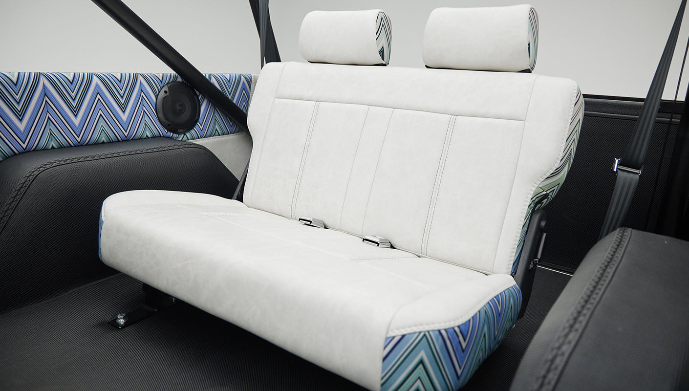Rear bench seat inside Classic Ford Bronco with white and patterned upholstery