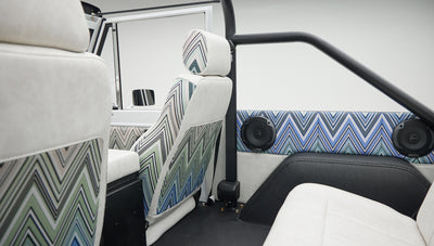 Rear interior of Classic Ford Bronco with patterned upholstery on seats and door panels, black roll bar