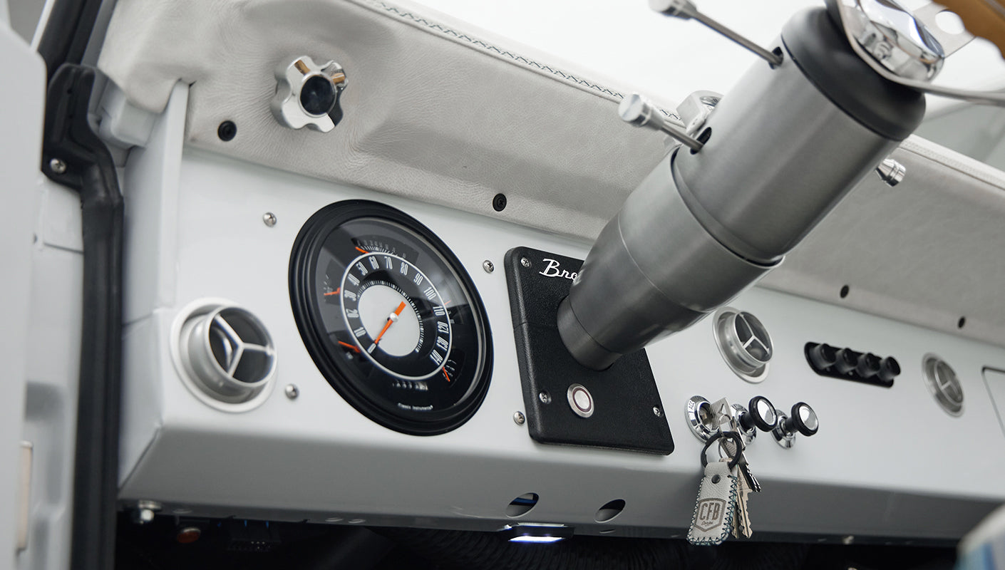 Dashboard close-up of Classic Ford Bronco showing speedometer, vents, and ignition with keys