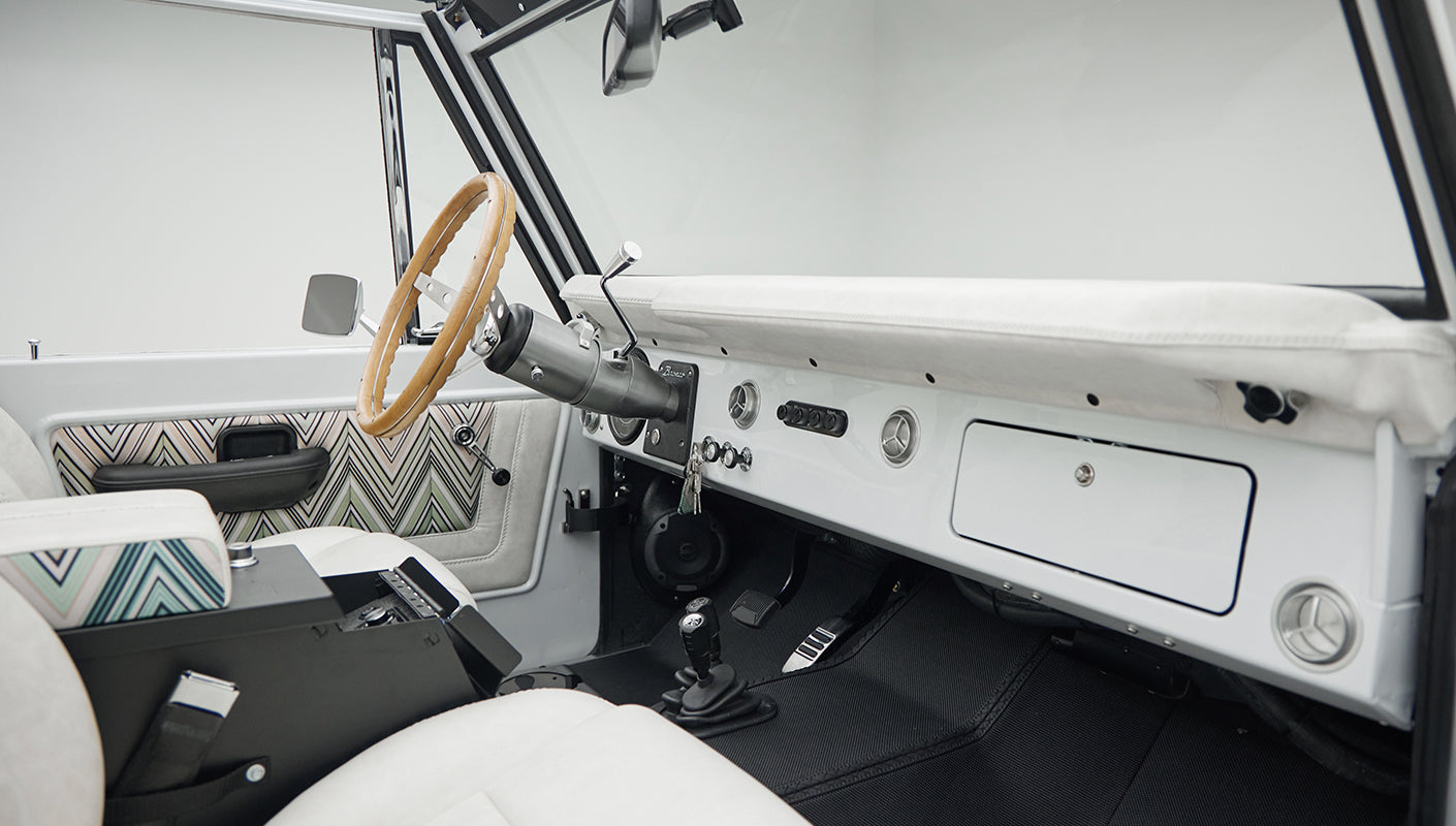 Classic Ford Bronco 1966 White Coyote Series interior with white and patterned seats and wooden steering wheel