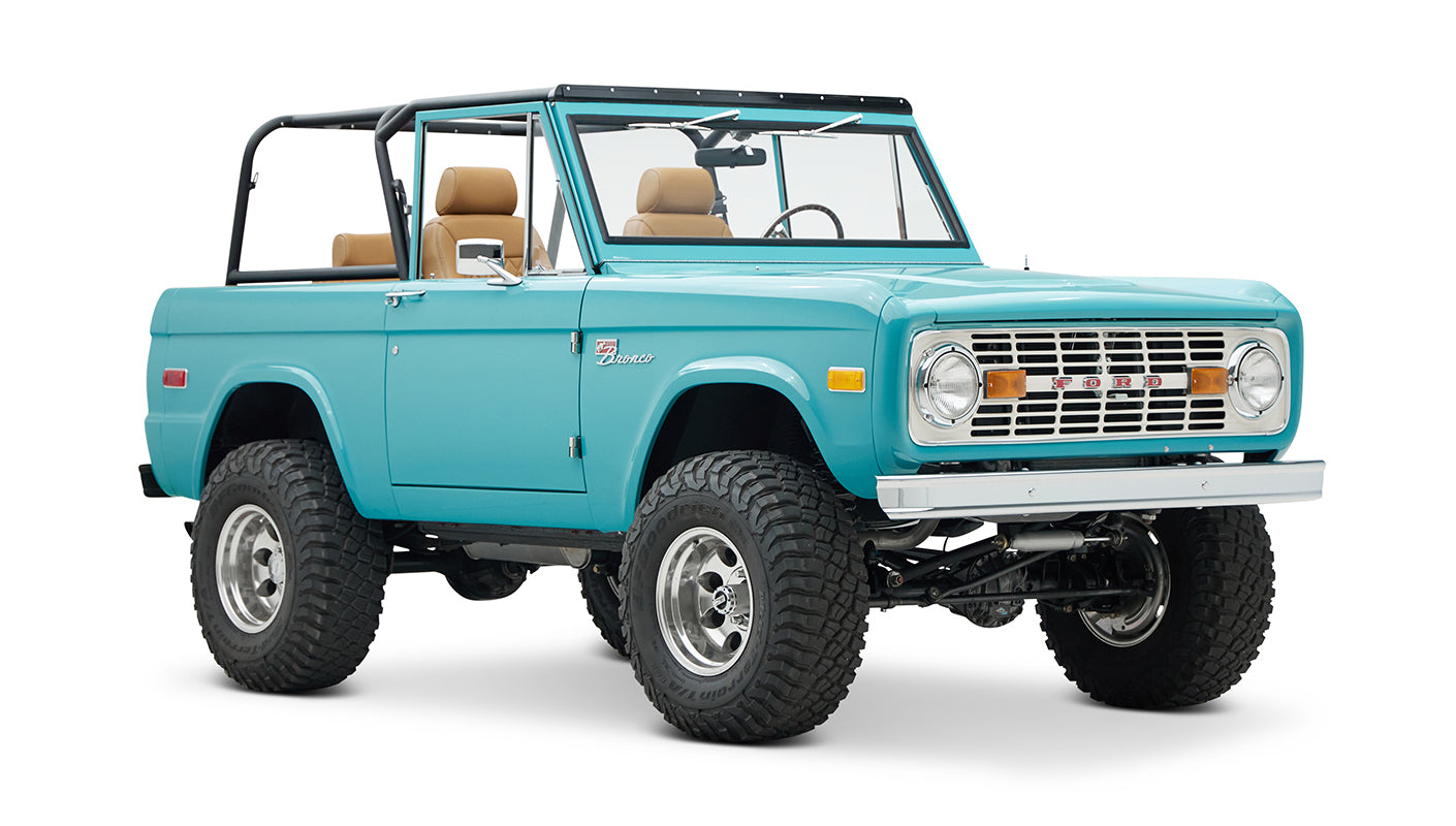 Classic Ford Bronco front 3-quarter view in bright turquoise with black roll cage and off-road tires