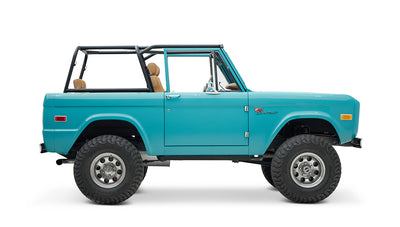 Side view of Classic Ford Bronco in Peacock Blue with tan seats and black roll cage, angled opposite side