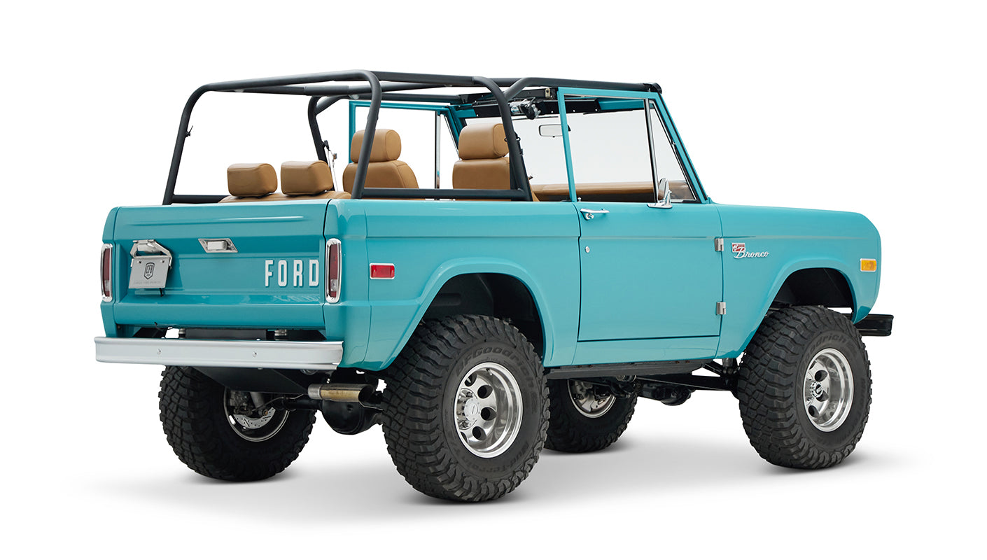 Classic Ford Bronco in Peacock Blue, tan interior, black roll cage seen from rear angled view