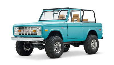 Classic Ford Bronco front 3-quarter view in bright turquoise with polished rims and black roll cage