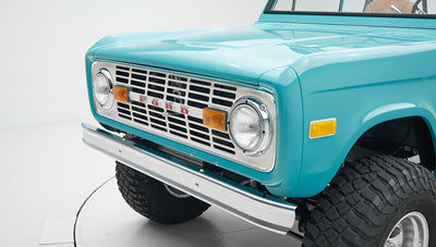 Close-up front grill of Classic Ford Bronco in Peacock Blue with round headlights and amber side lights