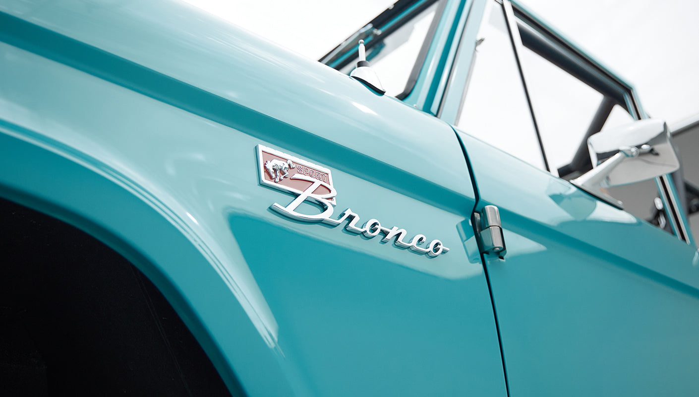 Close-up of Classic Ford Bronco logo emblem on front fender in Peacock Blue paint