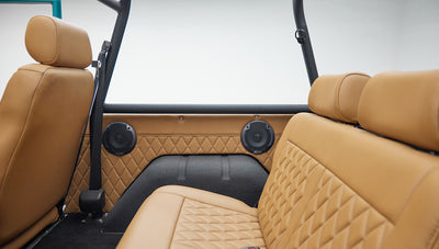 Back view of tan leather rear bench seat and speakers in door panels of classic Ford Bronco