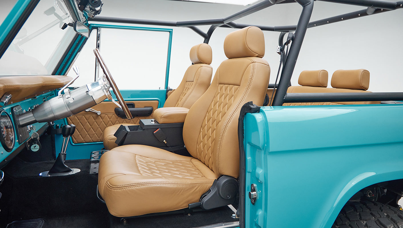 Interior front seating of Classic Ford Bronco with tan leather seats and black dashboard