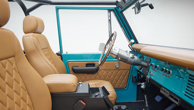 Driver and front passenger seats in tan leather with peacock blue interior door and dashboard