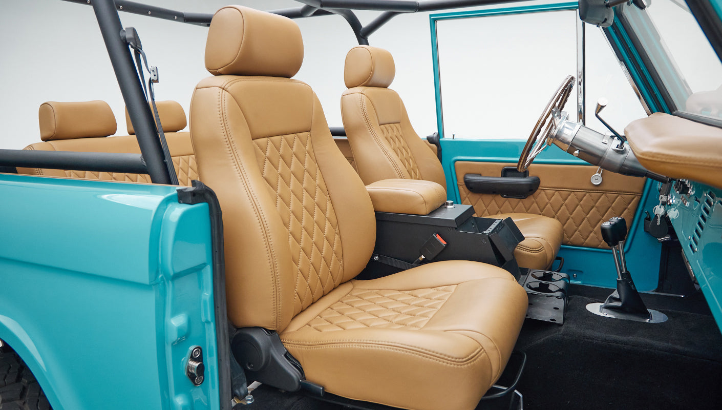 Interior front seats and center console of Classic Ford Bronco with tan diamond-stitched leather upholstery