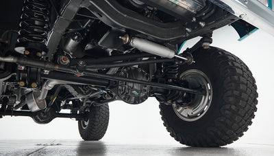 Undercarriage view showing black suspension components, coil springs, and a rugged tire of Classic Ford Bronco