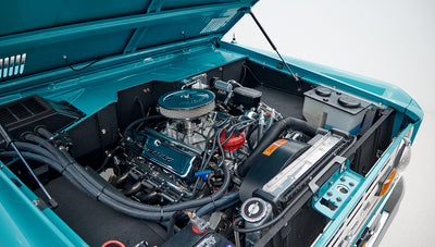 Open hood view revealing blue engine with chrome air cleaner and radiator components of Classic Ford Bronco