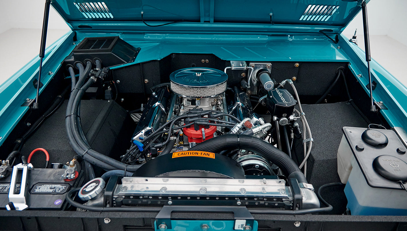 Open hood showing clean engine bay with blue paint and chrome components of Classic Ford Bronco
