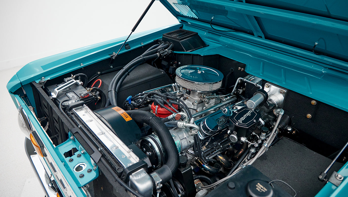 Close-up of Wilwood brake master cylinder and chrome Ford Racing valve covers in engine bay of Classic Ford Bronco