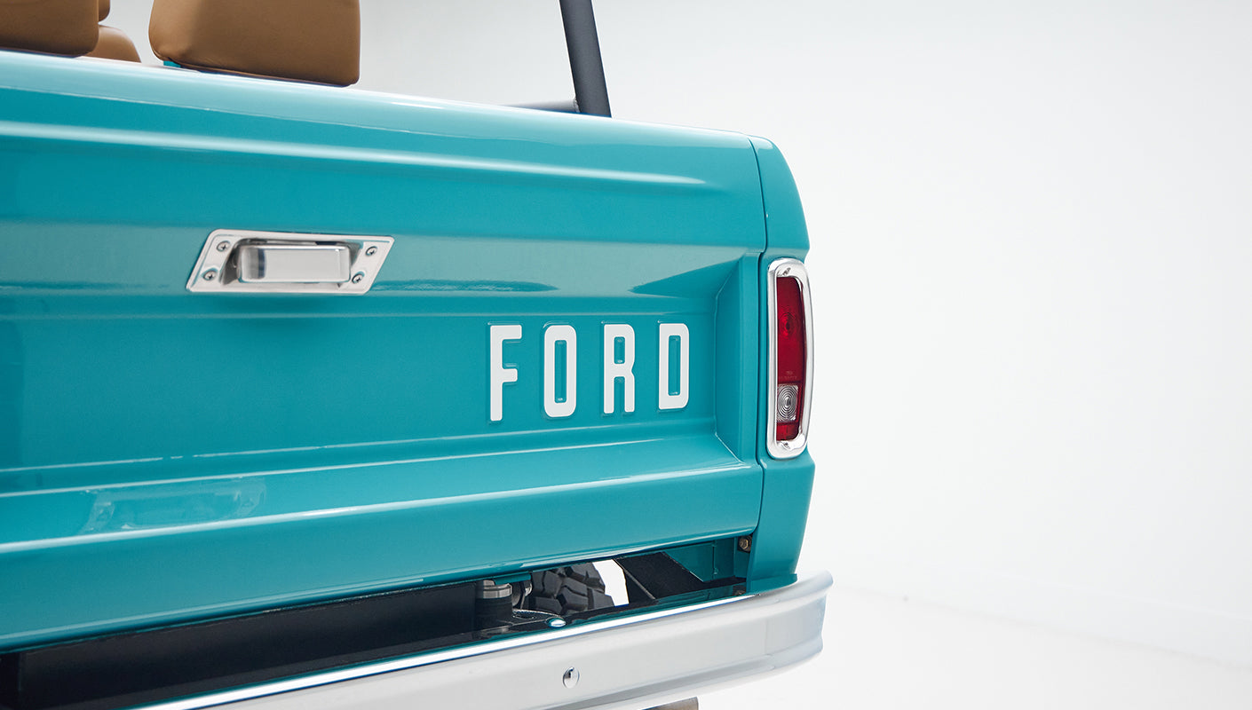Dashboard view with round speedometer, switches, and blue interior trim of Classic Ford Bronco